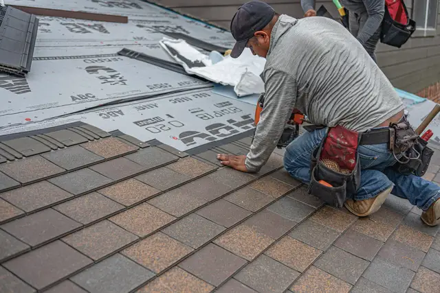 Roofer laying a new course of architectural shingles over underlayment