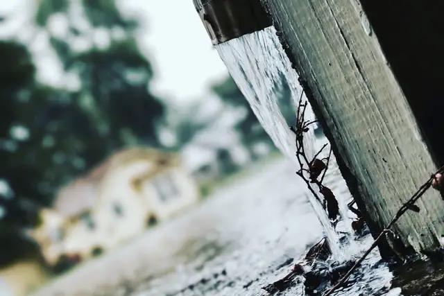 Rainwater pouring off a roof edge in a heavy storm