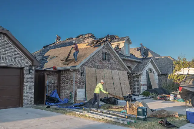 Crew stripping an old roof down to the deck on a brick house